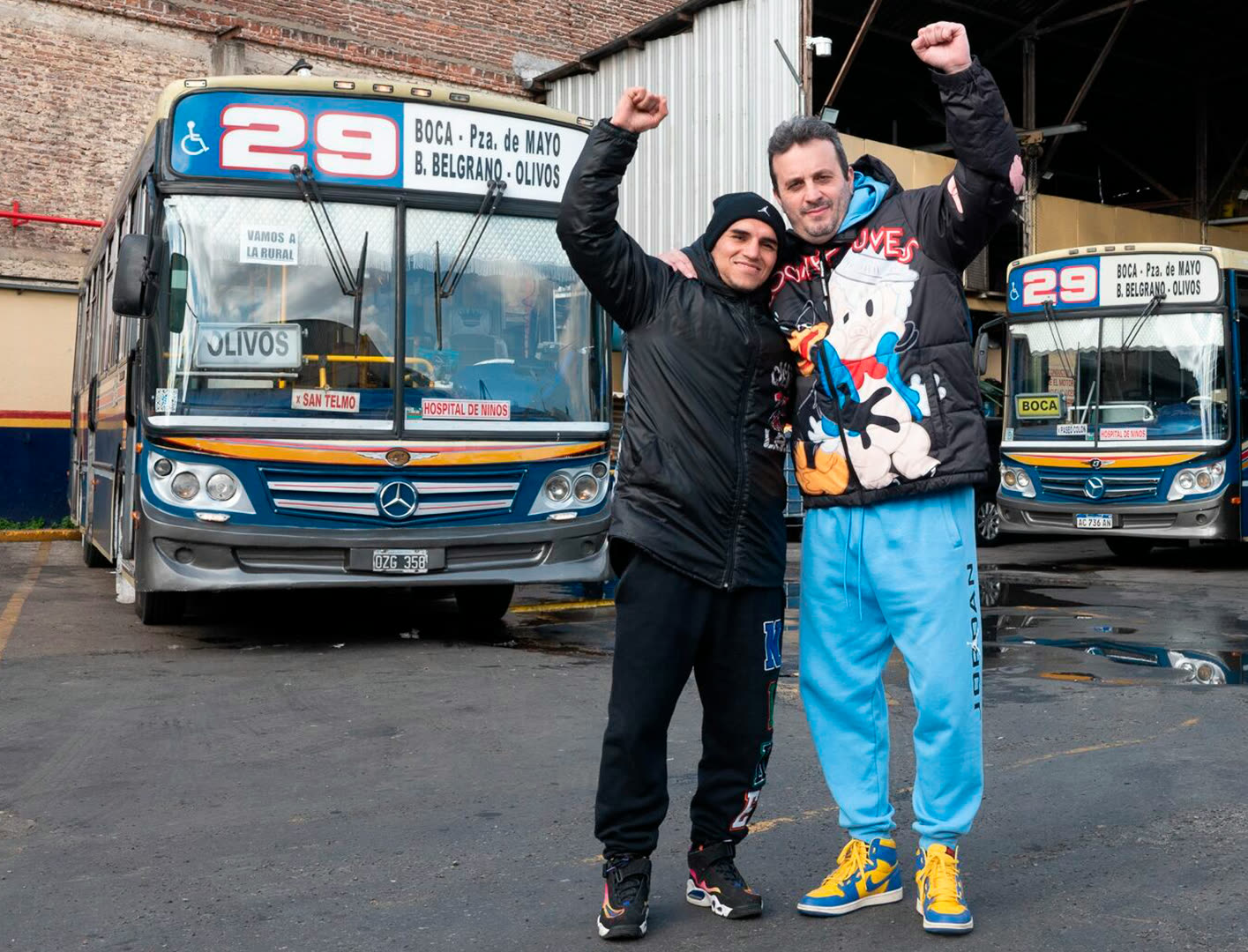 Rodrigo Calabrese y Fernando «Puma» Martínez, abrazados y con los puños en alto, frente a los colectivos de la Línea 29 en La Boca