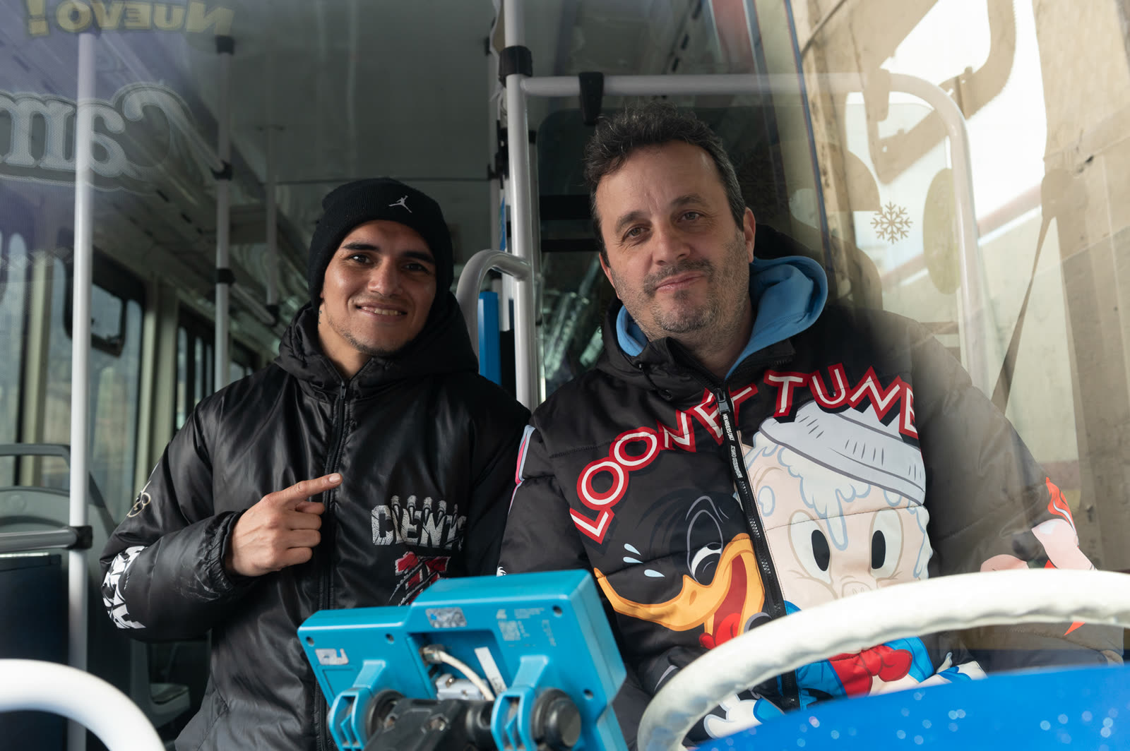 Rodrigo Calabrese y Fernando «Puma» Martínez sentados adentro de un colectivo de la Línea 29, vistos desde afuera del parabrisas